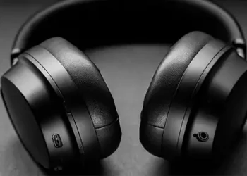 Schwarze Over-Ear-Kopfhörer auf einer schwarzen Tischplatte