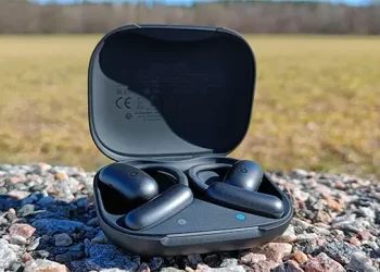 Komplettes schwarzes soundcore AeroFit 2 Set auf einem Schotterweg mit grünem Feld im Hintergrund