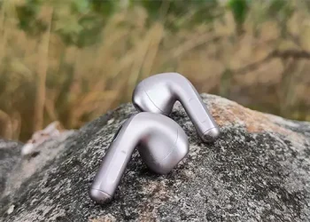 Ein Paar Xiaomi Buds 6 Nebula Purple auf einem großen Stein mit wogendem Gras im Hintergrund