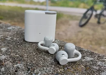Hellgraue CMF Clip Pro mit dem Ladecase im Hintergrund auf einer grauen Betonbarriere